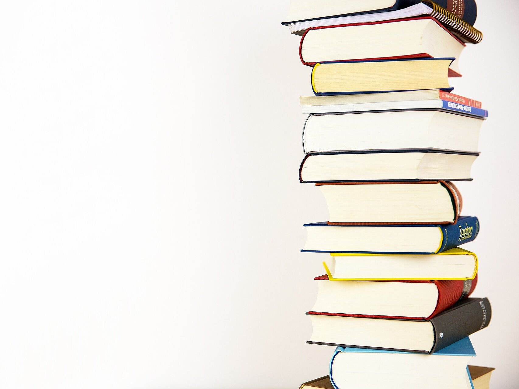 Stapel mit bunten Büchern vor weißem Hintergrund
