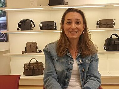 Nina Schator, Ausbildungsleitung PICARD Lederwaren sitzt vor einem Regal mit Taschen