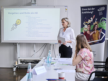 QuABB beim 7. FORUM Ausbildung von HessenChemie Barbara Emmelheinz vom QuABB-Team Wiesbaden stellt die Beratungsarbeit der Ausbildungsbegleitung in einem Workshop vor. Sie steht nebem einer Leinwand mit eine Powerpoint-Präsentation.