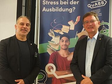 Bürgermeister Dirk Gene Hagelstein und Ausbildungsbegleiter Herr Jung vor einem QuABB-Rollup